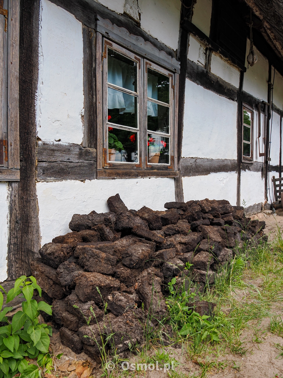 Ułożone pod ścianą domu, pod daszkiem suszą się kostki torfu, którym zimą palono w piecach